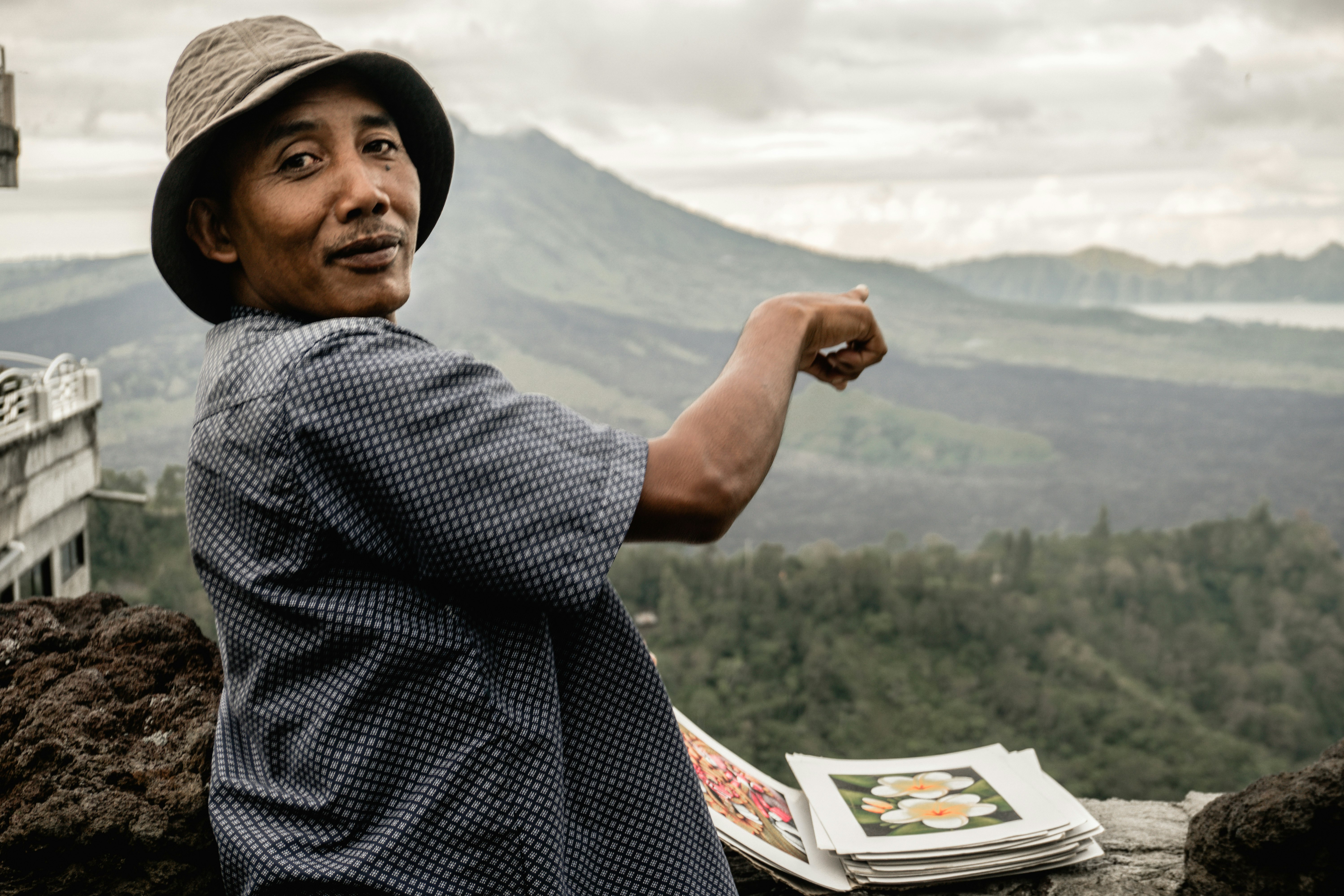 man in black and white checkered dress shirt standing on top of the mountain during daytime